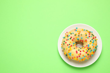 Delicious glazed donut on green background, top view. Space for text