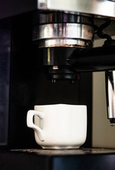 A coffee machine makes espresso in a small mug