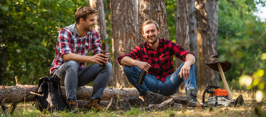 two men relax in forest. hiking and camping. male friendship. man best friend drink beer. ranger at...