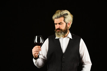 barman tasting red wine at degustation. male sommelier appreciating drink. glass of red wine....