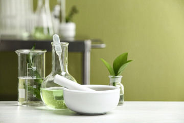 Mortar with pestle and natural ingredients on white table in cosmetic laboratory - obrazy, fototapety, plakaty