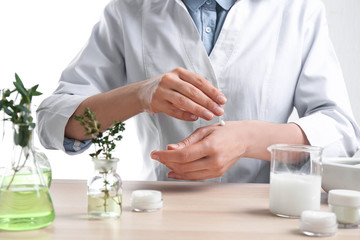 Obraz na płótnie Canvas Woman applying natural cream onto hand in cosmetic laboratory, closeup