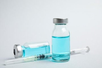 Vials and syringe on light background. Vaccination and immunization