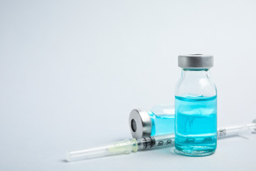 Vials and syringe on light background, space for text. Vaccination and immunization