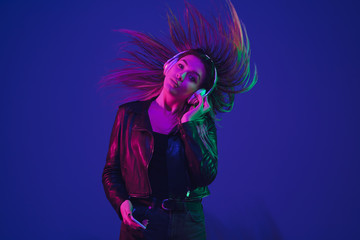 Dancing, hairs flying. Caucasian woman's portrait isolated on blue studio background in neon light. Beautiful female model. Concept of human emotions, facial expression, sales, ad. Trendy colors.