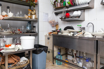 Restaraunt kitchen full of dirty dishes, crockery, tableware