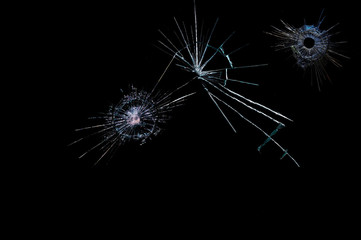 cracks on a black background on broken glass from bullet shots