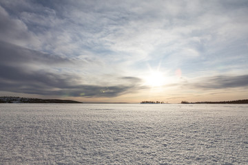 Bright winter sun over a field of ice. The magnificent landscape of the frozen lake. Cold winter background