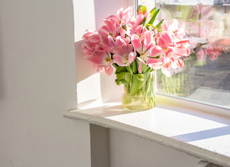bouquet of flowers in a vase on a wooden white windowsill