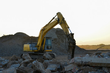 Crawler excavator with hydraulic breaker hammer for the destruction of concrete and hard rock at the construction site or quarry Backhoe works in a open pit. Roadworks background, texture