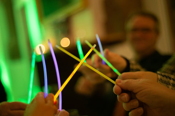 Freunde spielen mit Leuchtstäben auf einer Feier