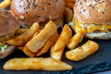 Hamburgers and French fries on dark textured background