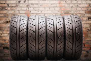 four summer tires, with drainage channels, very beautiful and modern safe, against the background of the brick wall of the garage. Auto tuning and spare parts