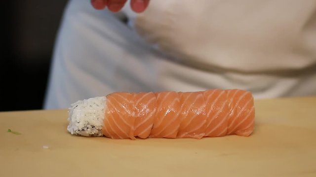 Chef's hands rolling a sushi roll. Sushi making process. Rolls the sushi roll