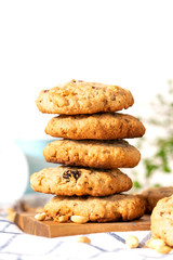 Homemade oat cookies with peanuts and raisins on the kitchen table, white background, free space for text. Stack of oatmeal cookies close-up, copy space.