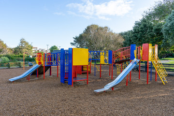 A colourful childrens climbing frame with metal slides in a a children's park