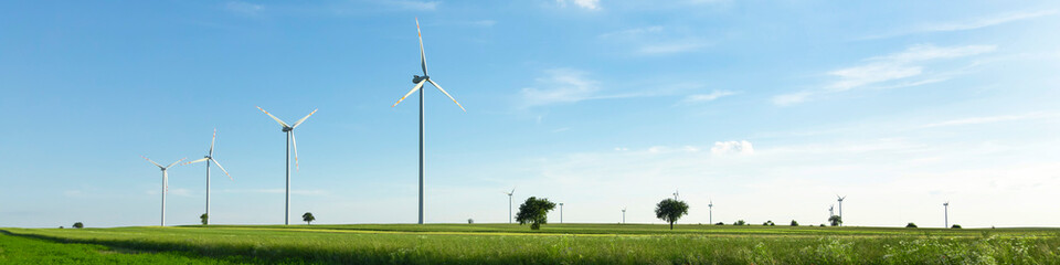 wind turbines in green field, countryside area with blue sky