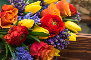 Bright spring bouquet of yellow tulips,blue hyacinths,speedwell,red ranunculus and orange roses...