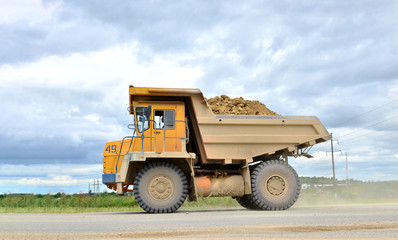 Big yellow mining truck working in the limestone open-pit. Loading and transportation of minerals in the dolomite mining quarry. Belarus, Vitebsk, in the largest dolomite deposit, quarry "Gralevo"