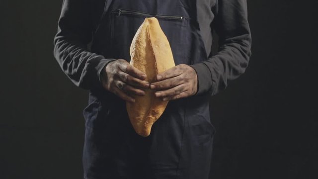 Close-up image of worker holding bread in hand.