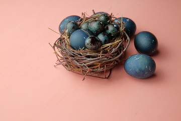 Eggs painted with a blue stone lie in a nest on a pink background, Easter.