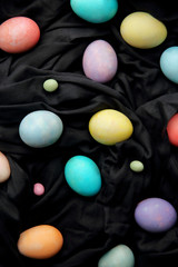 Colorful eggs and lollipops on a black background, Easter.