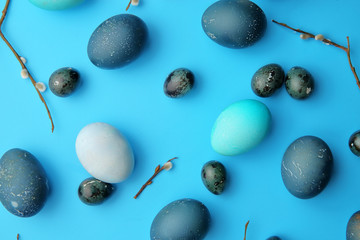 Easter, chicken and quail eggs on a pastel blue background with willow branches. The view from the top. Easter concept.