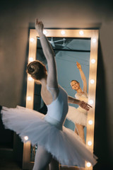 Fototapeta premium Elegant ballerina in white dress dancing in studio