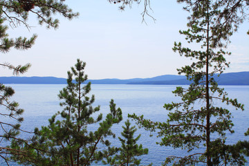 Beautiful view of the lake and the hills through the pine trees. Background. Scenery.