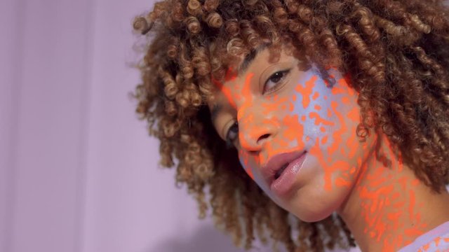 Closeup portrait of mixed race woman with neon art makeup on face. New beauty new identity concept