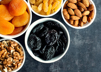 Dried fruits in white bowls on a dark background to maintain cardiovascular health top view