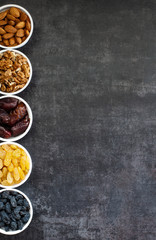 Dried fruits in white bowls on a dark background to maintain cardiovascular health top view