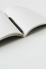 Open notebook with pen on white background. Minimal business concept.