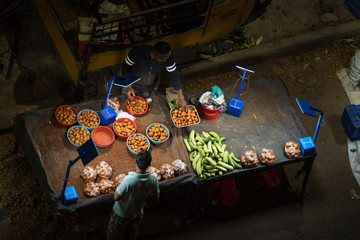 Man selling pototoes at street market stall in India - 329390696