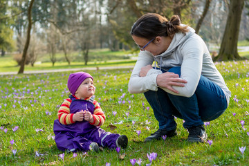 Mother and daughter exploring flowers in spring meadow.
