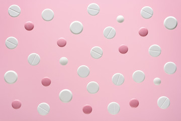 white and pink round medical pills on a color background