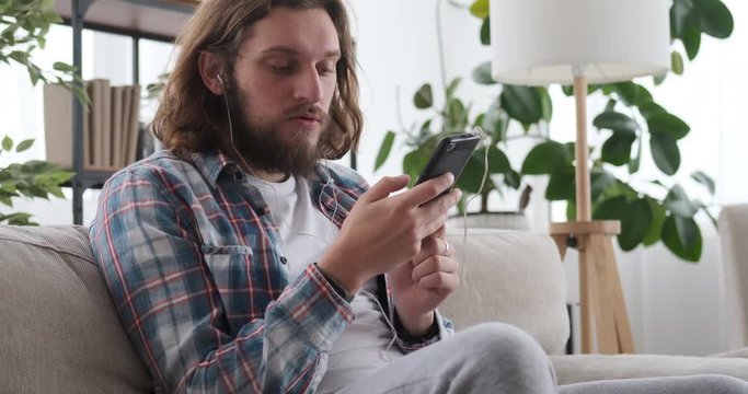 Man having fun listening music using headphones and mobile phone at home