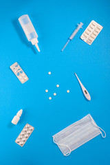 Viricides with mask and thermometer on a blue background. Vertical orientation, top view.