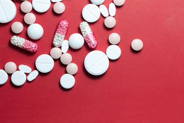 Fototapeta na wymiar Heap of white pills, tablets, capsules on red background. Drug prescription for treatment medication health care concept wth copy space.