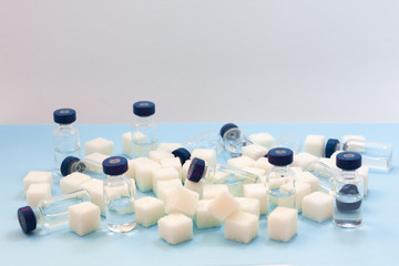 Sugar addiction, insulin resistance, unhealthy diet, sugar cubes and bottles of insulin on blue...