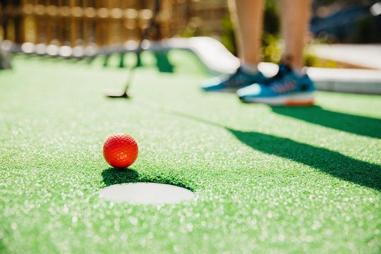 Surface level of golf ball near hole against man in golf course