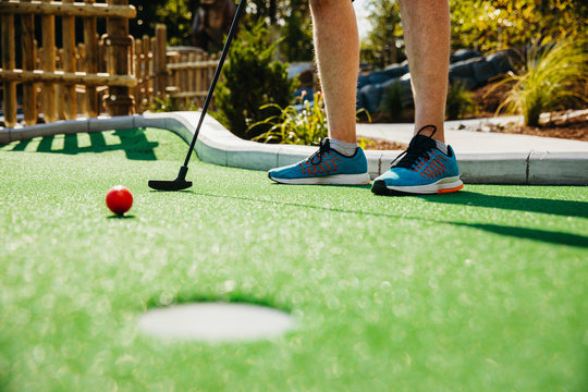 Low section of man taking shot at golf course in Raptor Falls Mini Golf