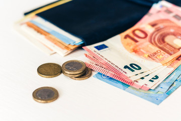 Close up money euro banknotes in blue purse and coins on white background.