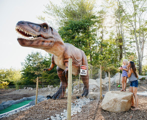 Mother holding amazed daughter while looking at dinosaur sculpture in miniature golf course © Cavan for Adobe