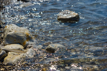 pebble stones on the sea beach, the rolling waves of the sea with foam