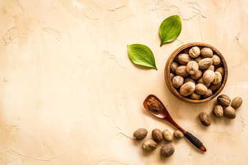 Obraz na płótnie Canvas Nutmeg - ground indian condiment in spoon - on beige background top-down copy space
