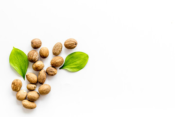 Nutmeg - whole nuts near leves - on white background top-down copy space