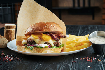 Appetizing and juicy burger with a large beef patty, melted cheddar cheese, arugula, onion, white...