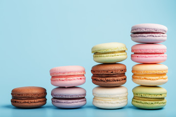 Multicolored French macaroni macaroni cookies are arranged in a pyramid on a blue background.