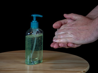 Liquid disinfection on wooden table used to wash hands, black background